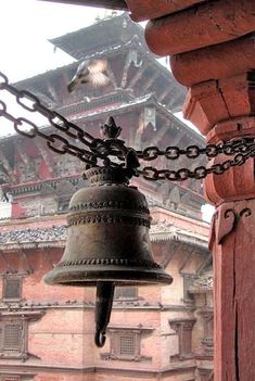 a bell hanging from the side of a building with a chain around it's neck