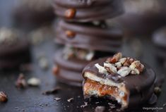 chocolate covered cookies with nuts on top and one broken in half, sitting on a table