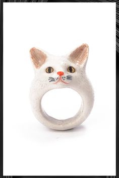 a white cat ring with an orange nose on it's face, sitting in front of a yellow background