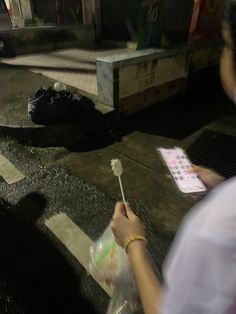 a person holding a plastic bag with a toothbrush in it and looking at something on the ground