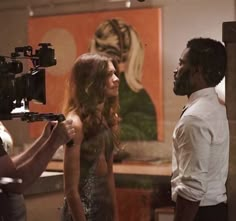 a man and woman standing next to each other in front of a painting on the wall