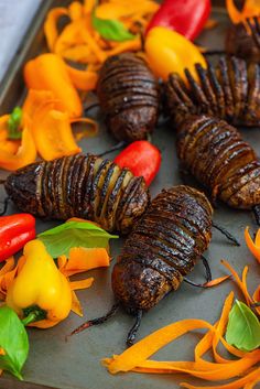 the caterpillars are being cooked on the grill with peppers and carrots