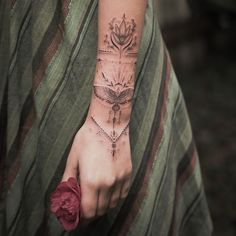 a woman's hand with tattoos on it and a flower in the middle of her wrist