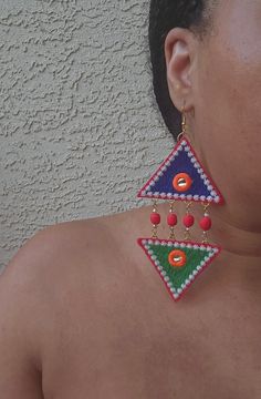 Enhance your outfit with the luxurious Harmony Crystal Triangle Earrings. The top and bottom mismatched design in vibrant green and blue is accented with red handmade clay beads, champagne glass crystals and amazonite semiprecious stones. Adorned with vibrant colors and a mirrored detail, these lightweight fabric earrings are wearable work of art. Item Details: Handmade Length: 5.5 Inches; Width: 2.5 Inches Closure: Ear wire; 18k gold plated & nickel free Materials: Polyester, Clay Beads, Glass Crystals Colors: blue, green, red, orange, white, silver, champagne, and gold Handmade Fabric Earrings, Bohemian Jeweled Beaded Earrings For Gifts, Unique Multicolor Earrings For Celebration, Unique Multicolor Beaded Earrings For Party, Green Beaded Earrings With Dangling Beads For Celebrations, Green Beaded Dangle Earrings For Celebration, Green Beaded Dangling Earrings For Celebration, Green Handmade Beaded Earrings For Celebrations, Handmade Green Beaded Earrings For Celebration