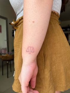 a woman with a tattoo on her left arm holding a scale and arrow in the other hand