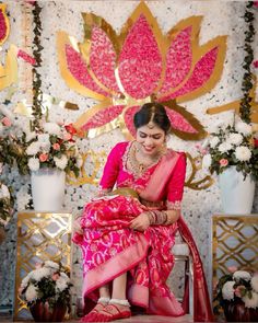 a woman sitting on top of a chair wearing a pink sari