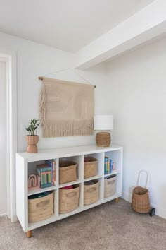 a white shelf filled with baskets and books