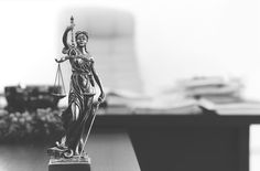 a statue of lady justice holding a scale in front of a cityscape background