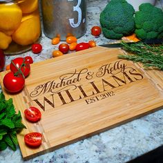 personalized cutting board with name and date on it surrounded by fresh fruits and vegetables