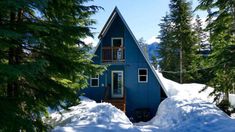 a blue house surrounded by snow and trees