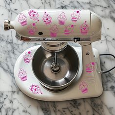 a mixer with cupcakes on it sitting on top of a marble countertop