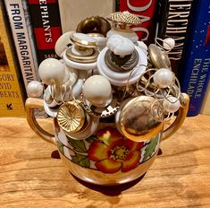 a coffee cup filled with lots of buttons and knobs on top of a wooden table