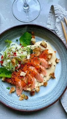 a blue plate topped with lots of food on top of a table next to wine glasses and utensils