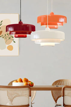 a dining room table with four chairs and two hanging lights above it that have fruit on them