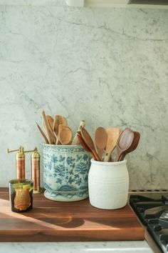 kitchen utensils and wooden spoons in a ceramic container on a counter top