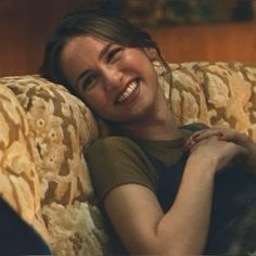 a woman laying on top of a couch smiling