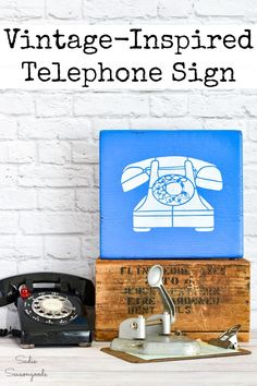 an old phone sitting on top of a wooden box with the words vintage - inspired telephone sign