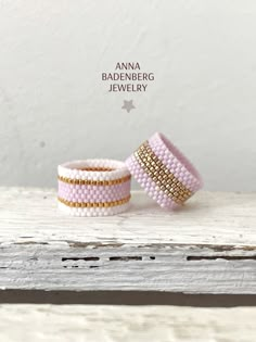 two pink and gold beaded bracelets sitting on top of a white wooden table