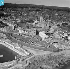 an old black and white photo of a city with lots of buildings on the shore