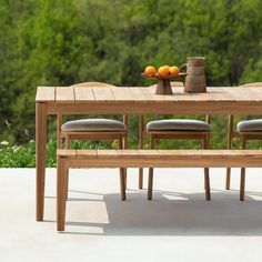 a wooden table with four chairs and a bowl of oranges on top of it