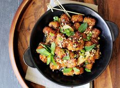 a black bowl filled with food on top of a wooden table