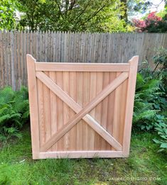 a wooden gate in the grass next to a fence