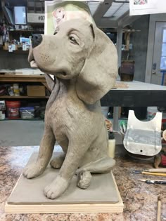 a statue of a dog sitting on top of a table next to paintbrushes