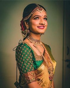 a woman in a green and gold sari smiles at the camera with her eyes closed