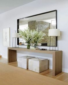 a large mirror sitting on top of a wooden table next to a vase filled with flowers