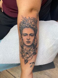 a woman's arm with a tattoo on it and flowers in her hair is shown