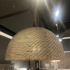 a large woven light fixture hanging from the ceiling in a room with other items on display