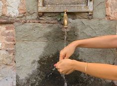 a woman is washing her hands with water from a faucet