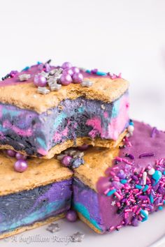 three pieces of cake on a plate with sprinkles and purple frosting