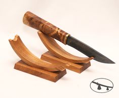 a wooden knife holder with a large knife on it's side and a smaller knife in the middle