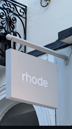 a sign hanging from the side of a building that says rhode on it