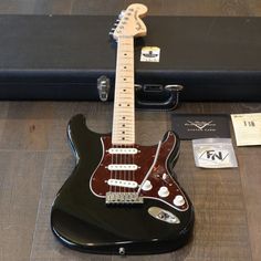 an electric guitar sitting on top of a wooden floor next to a hard shell case