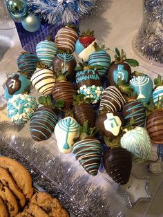 chocolate covered strawberries and cookies are on display in front of blue tinsels