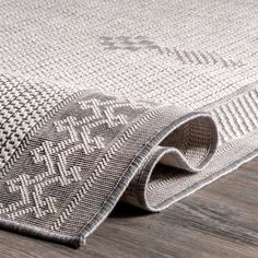 a rug on the floor is made from wood and has an intricate design in grey