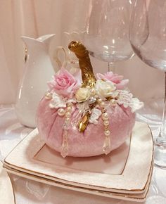 a pink purse sitting on top of a white plate next to wine glasses and a vase