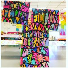 a woman standing in front of a colorful art piece that says happy birthday on it