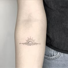 a small sun tattoo on the left arm