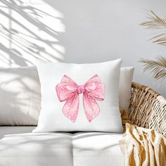 a pink bow pillow sitting on top of a couch next to a potted plant