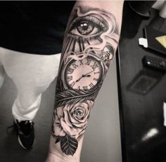 a man's arm with an eye and clock tattoo design on it, along with roses