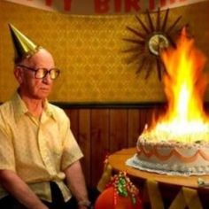 an older man sitting in front of a birthday cake