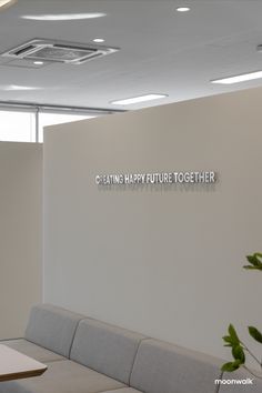 an office waiting area with two couches and a plant on the wall that says getting happy future together