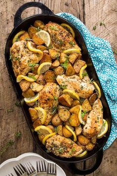 chicken with lemons and herbs in a cast iron skillet on a wooden table