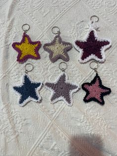 six crocheted star shaped keychains on a white tablecloth with a person's shadow in the background