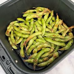 green beans are in a black container on the counter top, ready to be cooked