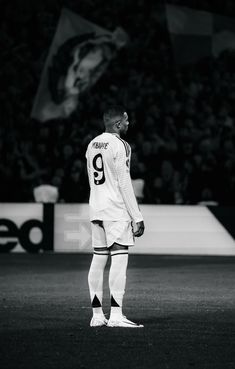 a man standing on top of a soccer field wearing a white uniform and black socks