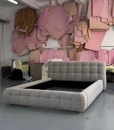 a couch sitting in front of a wall with pink and brown pieces of paper on it